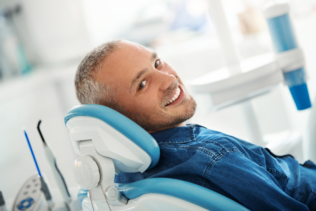 a smiling man sitting in a dental chair