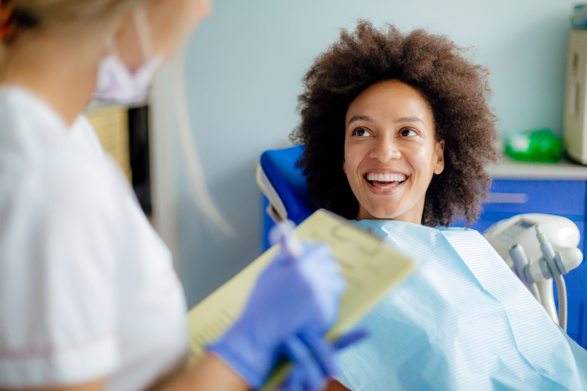 Woman sitting in dental chair talking to nurse